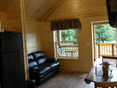 a living room with a leather couch in a log cabin at Camperland RV Resort & Cabins in Rosedale