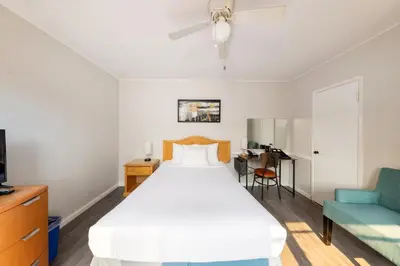 a bedroom with a white bed and a blue couch at 2400 Motel in Vancouver