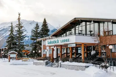 a building in the snow with mountains in the background at Lobstick Lodge in Jasper