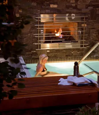 a woman in a swimming pool with a fireplace at Banff Aspen Lodge in Banff