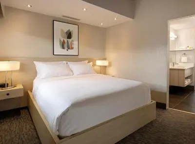 a bedroom with a large white bed and a bathroom at Banff Aspen Lodge in Banff