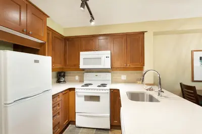 a kitchen with white appliances and wooden cabinets at Horstman House by Whistler Premier in Whistler