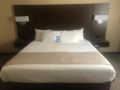 a bed with white pillows and a blue bottle on it at Days Inn by Wyndham Hinton in Hinton