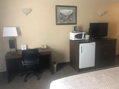a hotel room with a desk with a tv and a refrigerator at Days Inn by Wyndham Hinton in Hinton