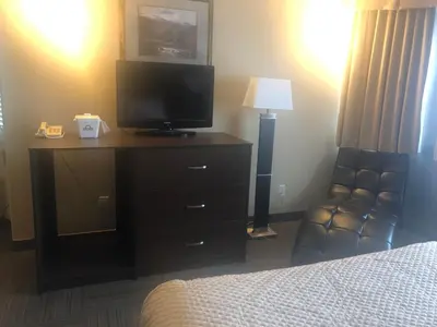 a hotel room with a tv and a dresser with a bed at Days Inn by Wyndham Hinton in Hinton