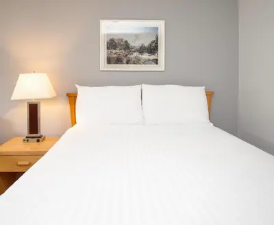 a bedroom with a large white bed and a lamp at Coast Hinton Hotel in Hinton