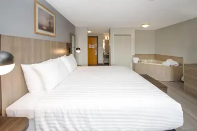 a bedroom with a large white bed and a bathroom at Coast Hinton Hotel in Hinton