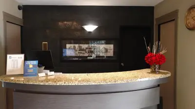 a lobby with a counter with a vase of red flowers at The Royal Anne Hotel in Kelowna