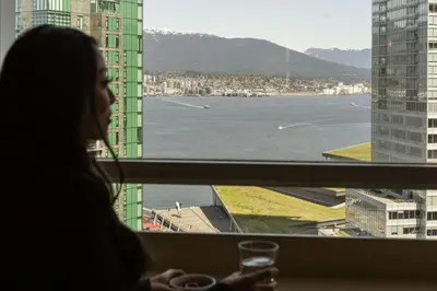 a woman looking out of a window at the water at Vancouver Marriott Pinnacle Downtown Hotel in Vancouver