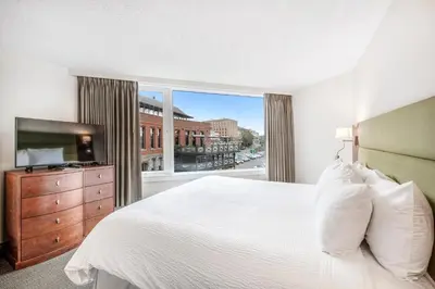 a bedroom with a large bed and a large window at Victoria Regent Waterfront Hotel & Suites in Victoria