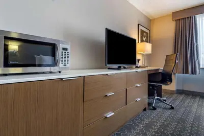 a hotel room with a desk with a microwave and a tv at Best Western Plus Vancouver Airport Hotel in Vancouver