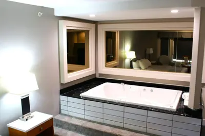 a bathroom with a tub and a large mirror at Western Budget Motel #1 Leduc/Nisku in Leduc