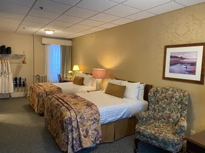 a hotel room with two beds and a chair at Kingston Hotel in Vancouver