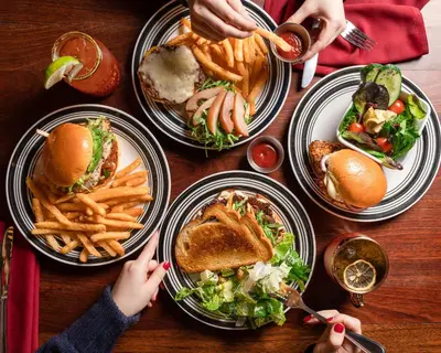 a wooden table with plates of food and french fries at Kingston Hotel in Vancouver
