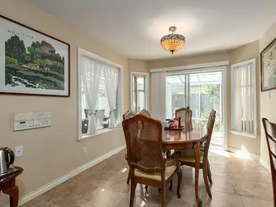a dining room with a table and chairs and windows at Fraser River Richmond Bed and Breakfast in Richmond