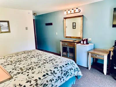 a bedroom with a bed and a mirror and a sink at Three Valley Lake Chateau in Revelstoke