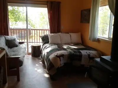 a bedroom with a bed and a couch and a window at Eagle Bear Lodge in Tatla Lake