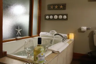 a bathroom with a tub with a bottle of wine and glasses at Great Condo In Excellent Location - Waterfront Building - Seaside in Ucluelet