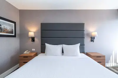 a bedroom with a large bed with white sheets and two lamps at Sandman Hotel Victoria in Victoria