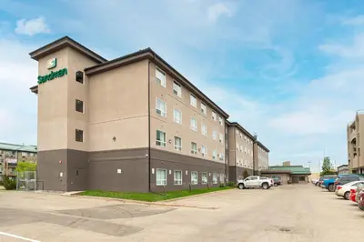a large building with a parking lot in front of it at Sandman Hotel Grande Prairie in Grande Prairie