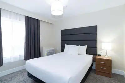a bedroom with a white bed and a large window at Sandman Hotel Grande Prairie in Grande Prairie