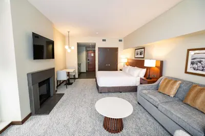 a hotel room with a bed and a couch and a bed and a room with at Sutton Place Hotel Revelstoke Mountain Resort in Revelstoke