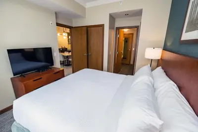 a bedroom with a white bed and a flat screen tv at Sutton Place Hotel Revelstoke Mountain Resort in Revelstoke