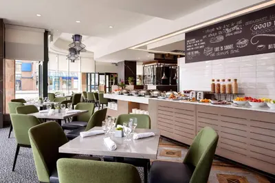 a restaurant with tables and chairs and a counter at Vancouver Airport Marriott Hotel in Richmond