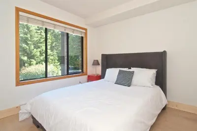 a bedroom with a large white bed with a window at Powderhorn by Whistler Blackcomb Vacation Rentals in Whistler