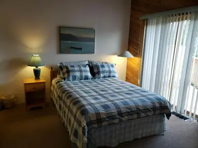 a bedroom with a bed with a blue and white blanket at Invermere 4 Br Lakeside, Mountain View Home! Walk to Sandy Beach for Swimming, Boating, Tennis and Beach Volleyball Local Town Shopping, Eateries, Bakery and Pubs! Welcome Family's, Healthcare Workers and Trades! Monthly Rentals of 28 Nights or More! in Invermere