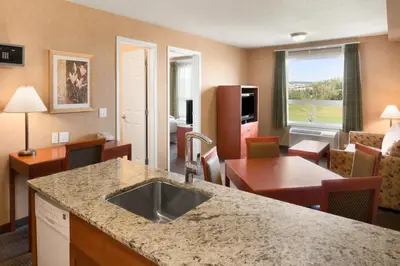a kitchen and living room with a sink in a hotel room at Days Inn & Suites by Wyndham Cochrane in Cochrane