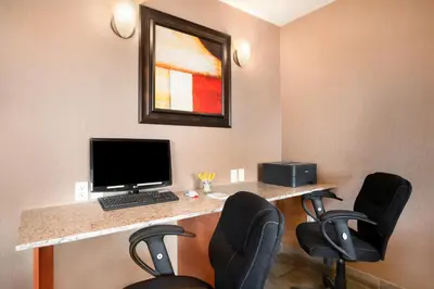 a room with a desk with a computer and chairs at Days Inn & Suites by Wyndham Cochrane in Cochrane