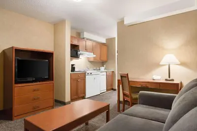 a living room with a couch and a kitchen at Days Inn & Suites by Wyndham Cochrane in Cochrane