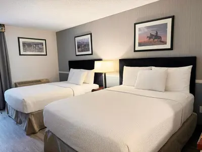 a hotel room with two beds with white sheets at Divya Sutra Plaza and Conference Centre Calgary Airport in Calgary