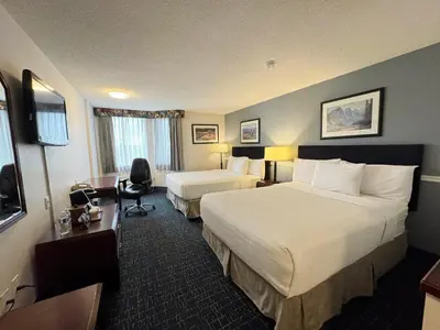 a hotel room with two beds and a desk at Divya Sutra Plaza and Conference Centre Calgary Airport in Calgary