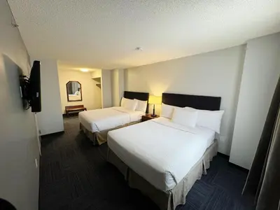 a hotel room with two beds and a television at Divya Sutra Plaza and Conference Centre Calgary Airport in Calgary