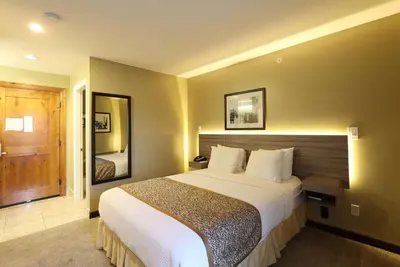 a hotel room with a large bed and a mirror at Days Inn by Wyndham Surrey in Surrey