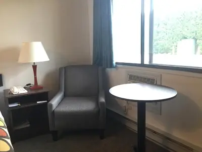 a room with a chair and a table and a window at Super 8 by Wyndham Kelowna BC in Kelowna