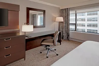 a hotel room with a desk and a chair and a mirror at The Westin Calgary in Calgary