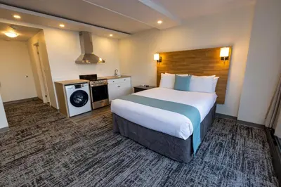a hotel room with a large bed and a kitchen at Highliner Hotel in Prince Rupert