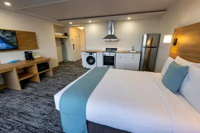 a hotel room with a large bed and a kitchen at Highliner Hotel in Prince Rupert