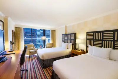 a hotel room with two beds and a desk at Pinnacle Hotel Harbourfront in Vancouver