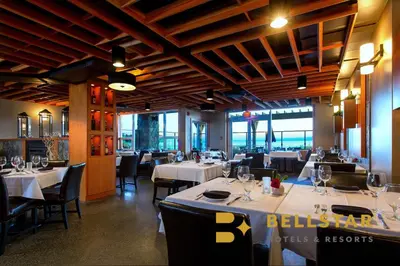 a dining room with white tables and chairs and windows at The Beach Club Resort — Bellstar Hotels & Resorts in Parksville