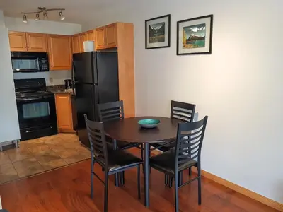 a kitchen with a table and chairs and a black refrigerator at PRC Annex - Pet Friendly in Canmore