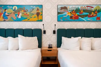 two beds in a hotel room with two posters on the wall at The Dorothy Motel in Banff
