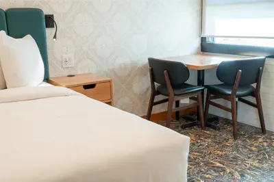 a room with a bed and two chairs and a table at The Dorothy Motel in Banff