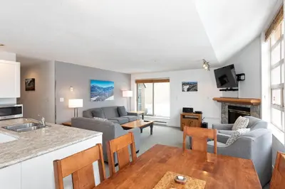 a kitchen and living room with a couch and a table at Lake Placid Lodge by Whiski Jack in Whistler