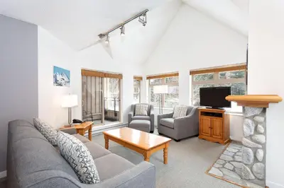 a living room with a couch and a tv at Lake Placid Lodge by Whiski Jack in Whistler