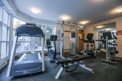 a gym with several tread machines in a room at The Woodrun Lodge by Whiski Jack in Whistler