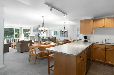 a kitchen and living room with a table and chairs at The Woodrun Lodge by Whiski Jack in Whistler